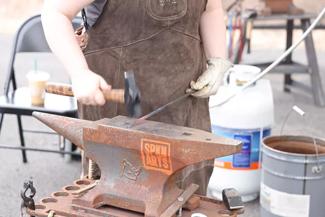 A blacksmith works hot metal at CFI's Spring Hammer-In, June 2024