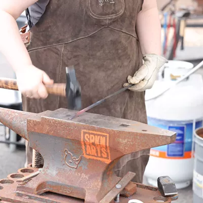 Image: A blacksmith works hot metal at CFI's Spring Hammer-In, June 2024