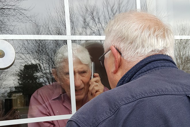 A father sees his son for the final time through a pane of glass at a Lewiston nursing home